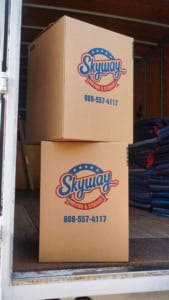 Two large Skyway Moving & Storage boxes stacked at the back of a truck next to folded moving blankets.